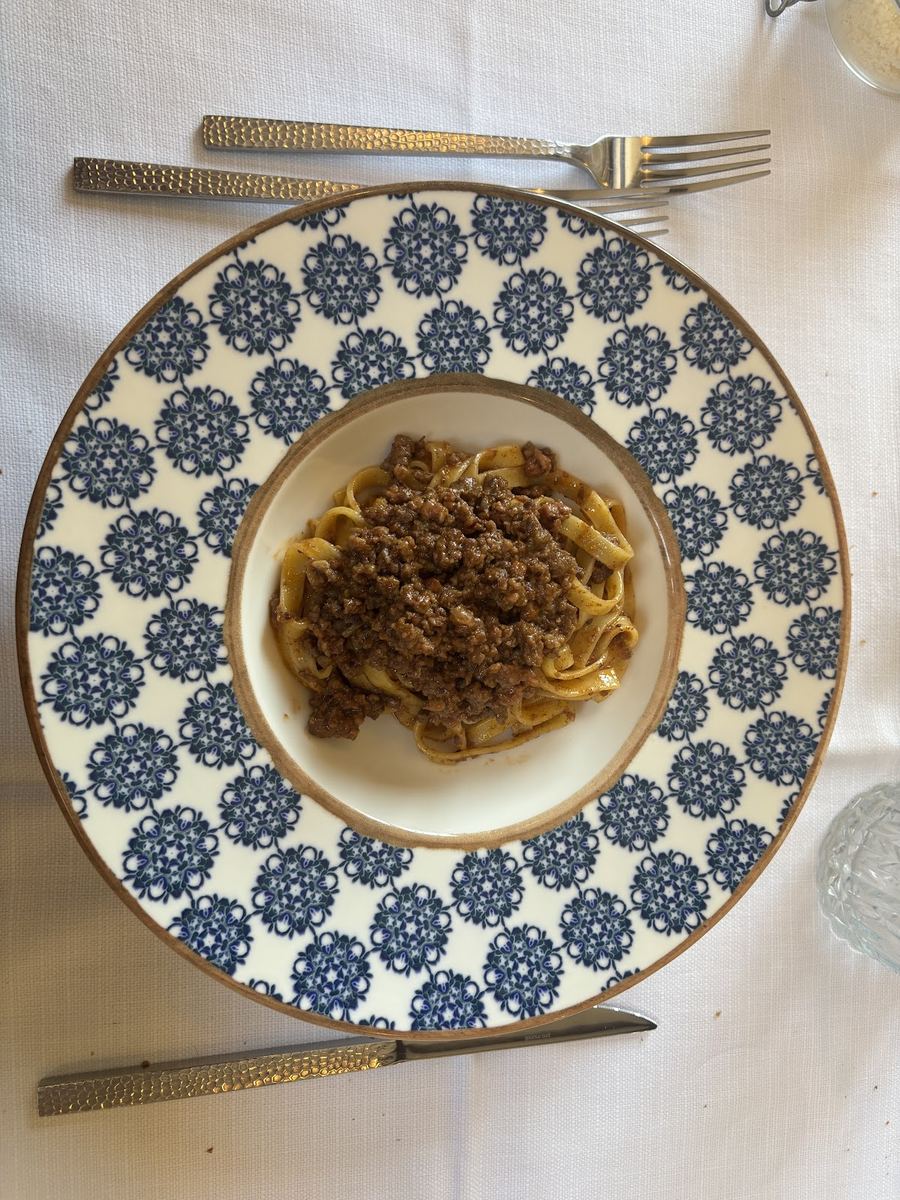 Tagliatelle al ragù servite su un piatto in ceramica blu e bianca